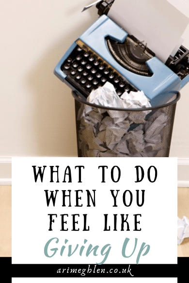 Photo of a blue typewriter sitting in a trash can that is full of scrunched up paper. Text overlay reads What to do when you feel like giving up. AriMeghlen.co.uk