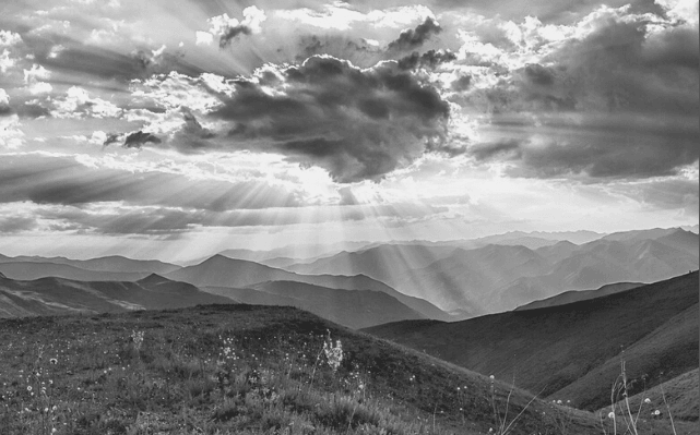 Featured Images - Black and white photo of a landscape featuring hills, meadow and sunlight streaming behind the clouds. Image from Pixabay