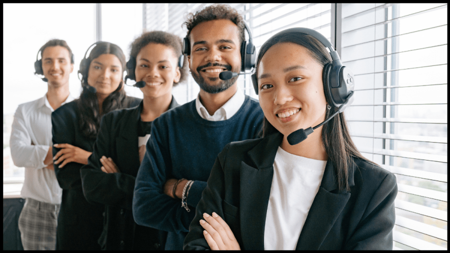 Photo of two women and a man, standing in a line, each wearing a headset and smiling.