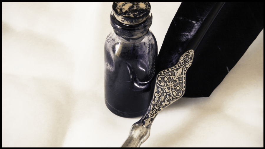 Photo of a black feather quill pen beside a narrow, corked, glass bottle full of dark ink.