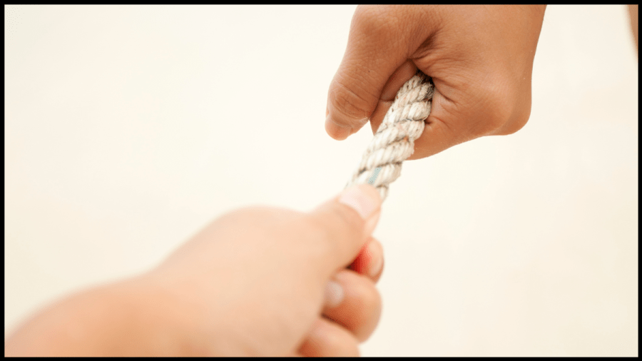 Photo of two hands each pulling against a rope. Tug of war