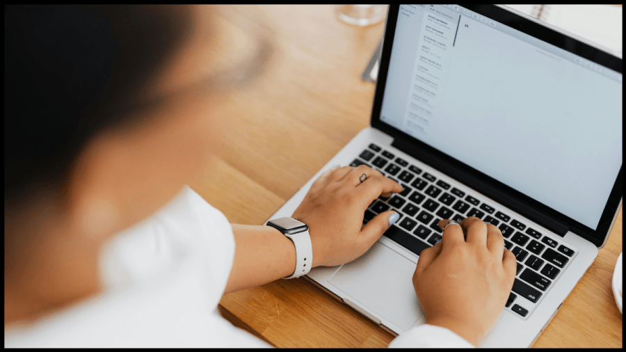 Photo of a laptop open and hands on the keyboard.