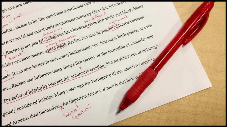 Photo of paper with red edits on the text and a red pen resting on the paper