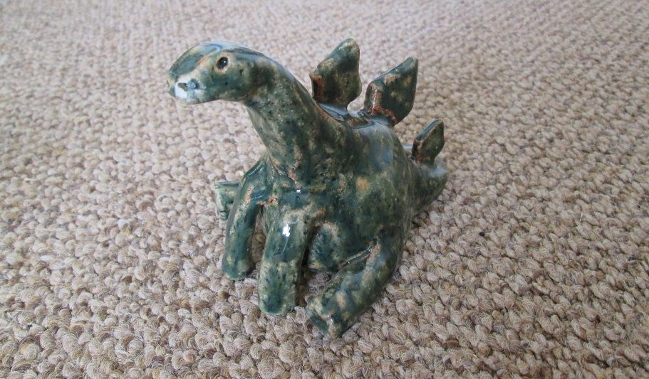 pottery sculpture of a stegosaurus sitting