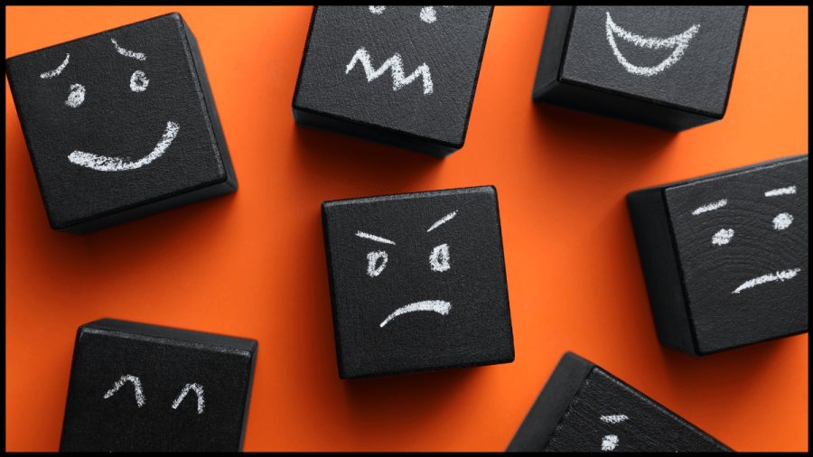Picture of Black cubes with different facial expressions drawn on in white.