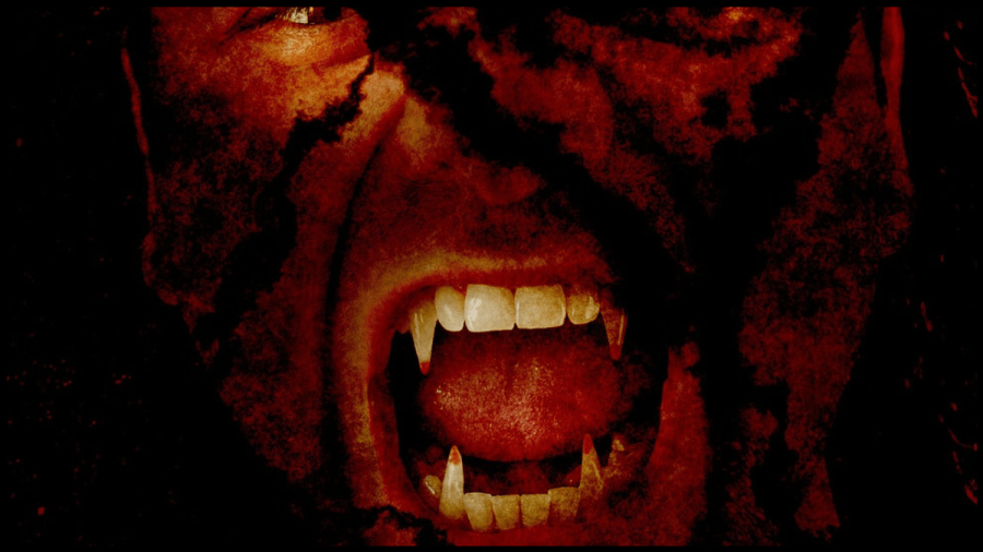 Close up of a scary man's face with mouth open exposing vampire fangs