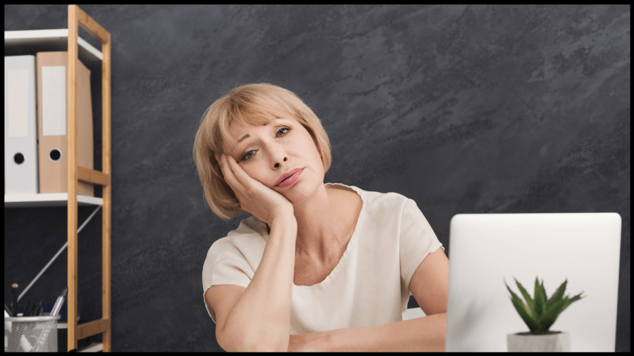 Photo of a blonde haird woman, resting her head in her palm, looking bored.