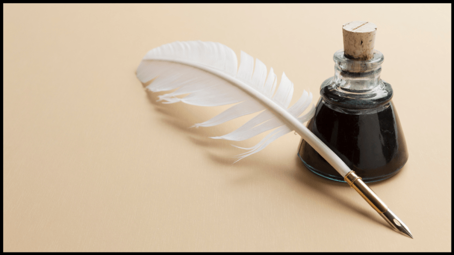 Photo of a white feather quill pen and a bottle of black ink with a cork stopper
