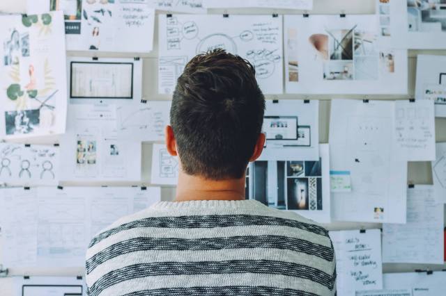Have a plan. Man standing before a noticeboard of notes