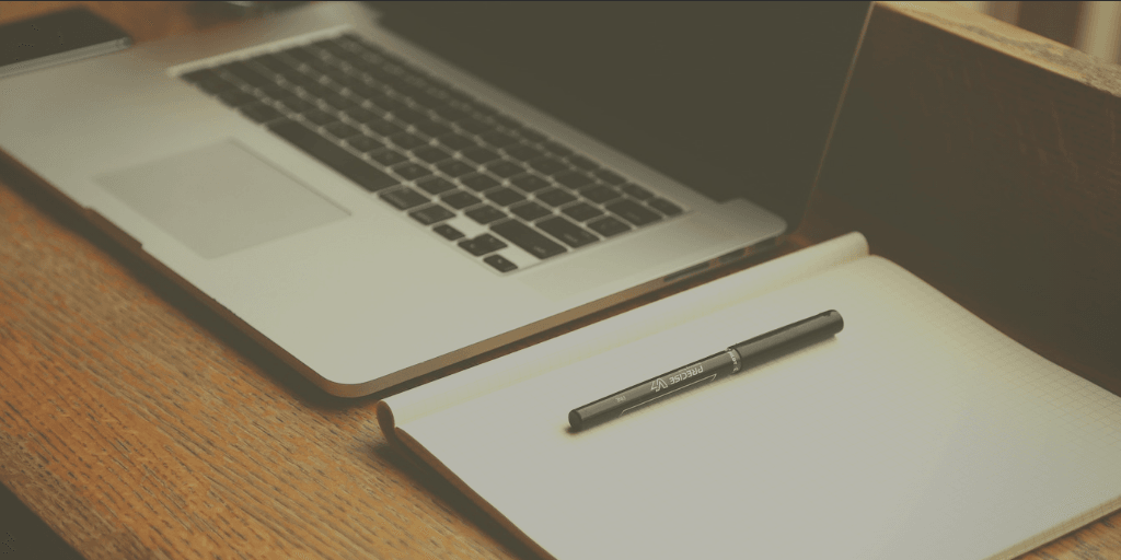 Photo of laptop and notepad on desk