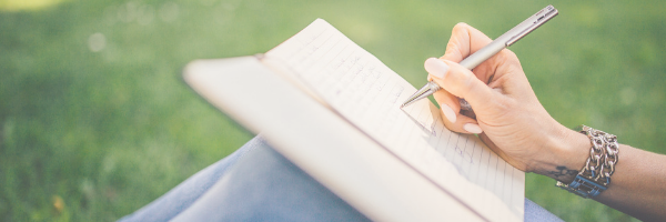 Woman writing in a diary on her knee.  Image from Pixabay