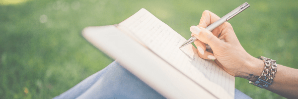 Woman writing in a diary on her knee.  Image from Pixabay