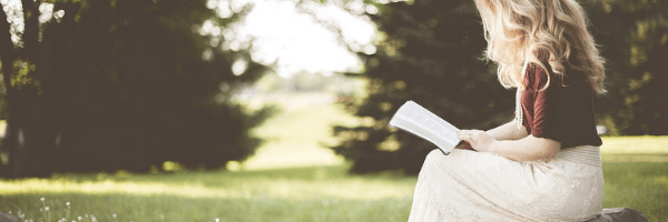 Young blonde woman reading in a field.  Image from Pixabay