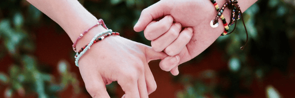 Image of two hands holding pinky fingers. Friendship