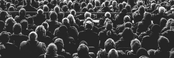 Black and white photo of a large group of people sitting. Image from Pixabay