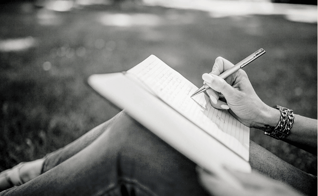 Featured Images - Image of a woman's hand writing in a notepad resting on her knee. Image from Pixabay