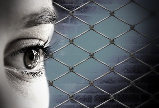 Woman imprisoned. Day of the Imprisoned Writer. Close up of a woman's eye with prison fencing behind.