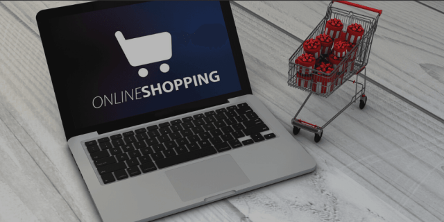 Blog Image - Laptop with "online Shopping" written across the screen. Small shopping cart full of presents. Ecommerce