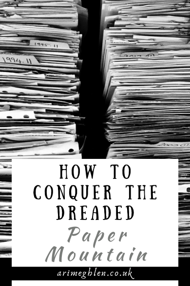Black and white photo of stacks of paper. Text overlay reads How to Conquer the Dreaded Paper Mountain. AriMeghlen.co.uk
