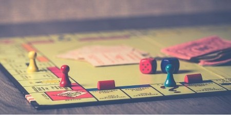 Blog Image - Photo of the boardgame Monopoly, with several pieces on the board, cards, money and dice