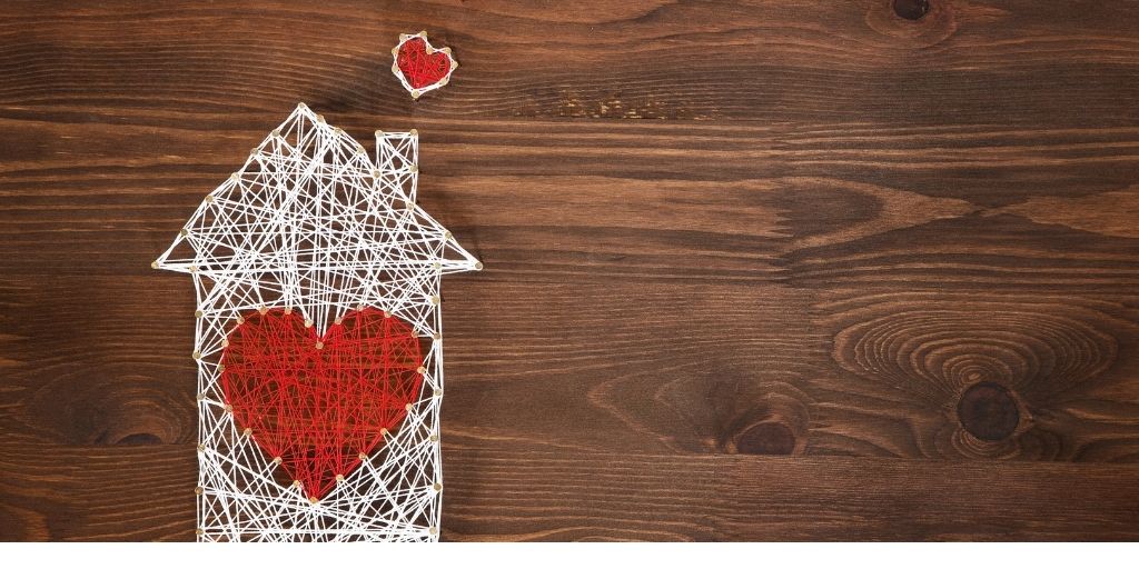 Image of a house made from thread with a red heart in the middle. Image from Canva
