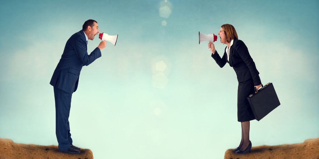 Image of a man and woman standing on opposite sides of a chasm each shouting into a megaphone