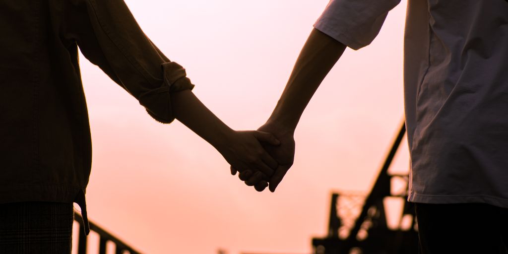 Photo of a couple holding hands, the photo is focused on the clasped hands