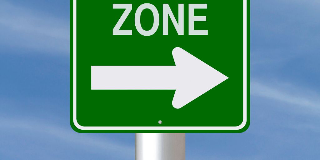 Photo of a green sign with white writing that reads Zone and a white arrow. Image from Canva Pro
