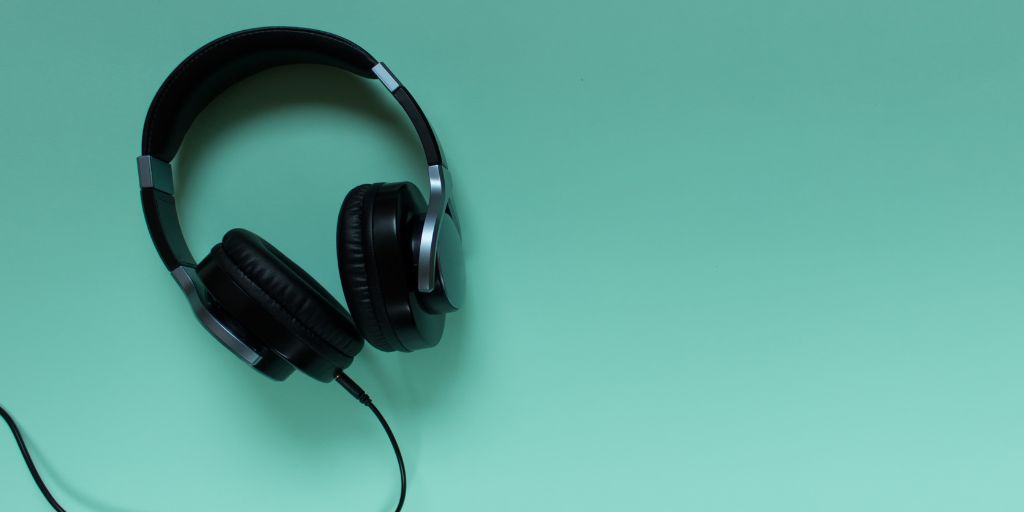 Photo of black headphones with wire on a green background. Image from Canva