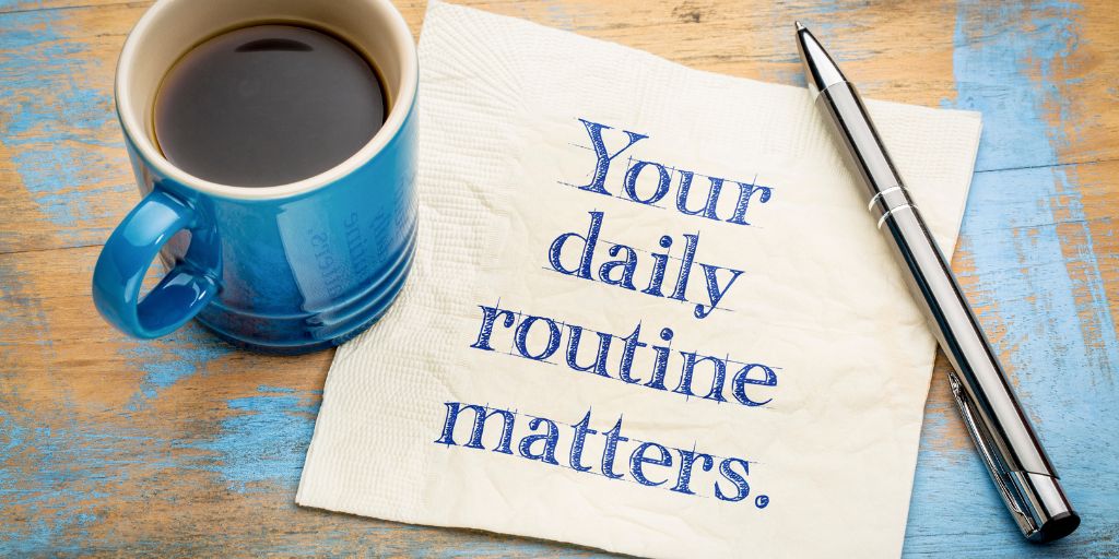 Photo of a napkin with the words Your daily routine matters written on. A cup of coffee and a pen. Image from Canva