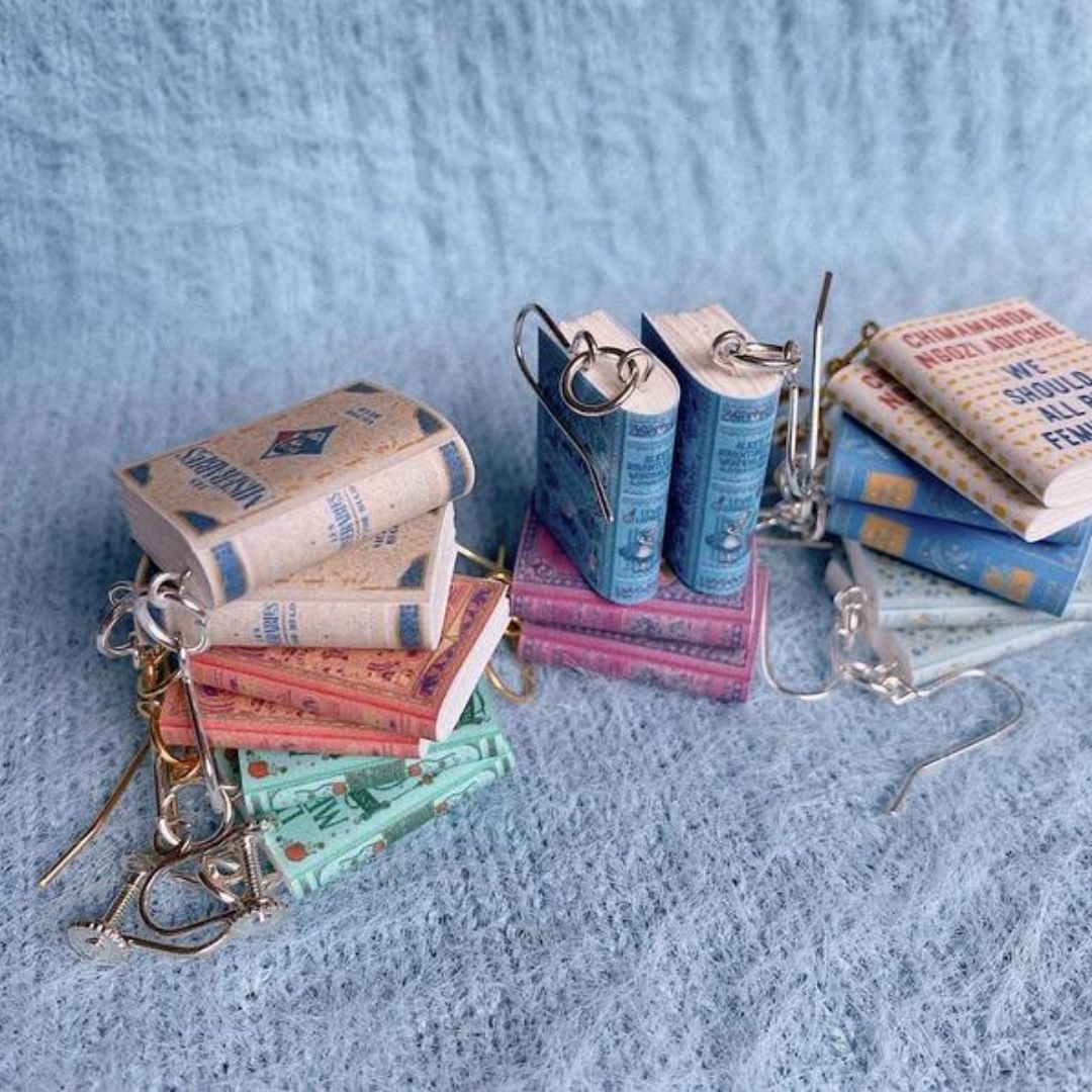 Collection of bookish earrings. Each one is a miniature book with a detailed cover and hangs with fishhook ear wire. Available at HappyFutureStudio on Etsy