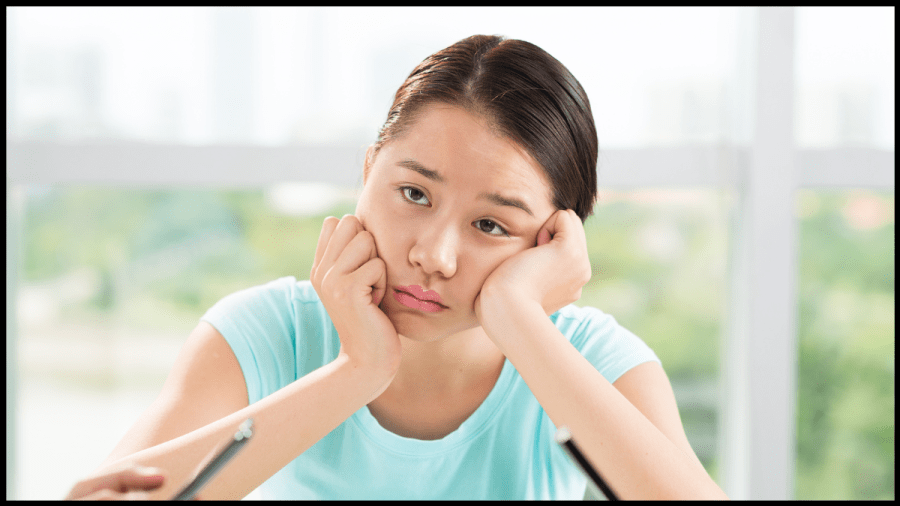 Photo of a young woman in a blue t-shirt, looking bored