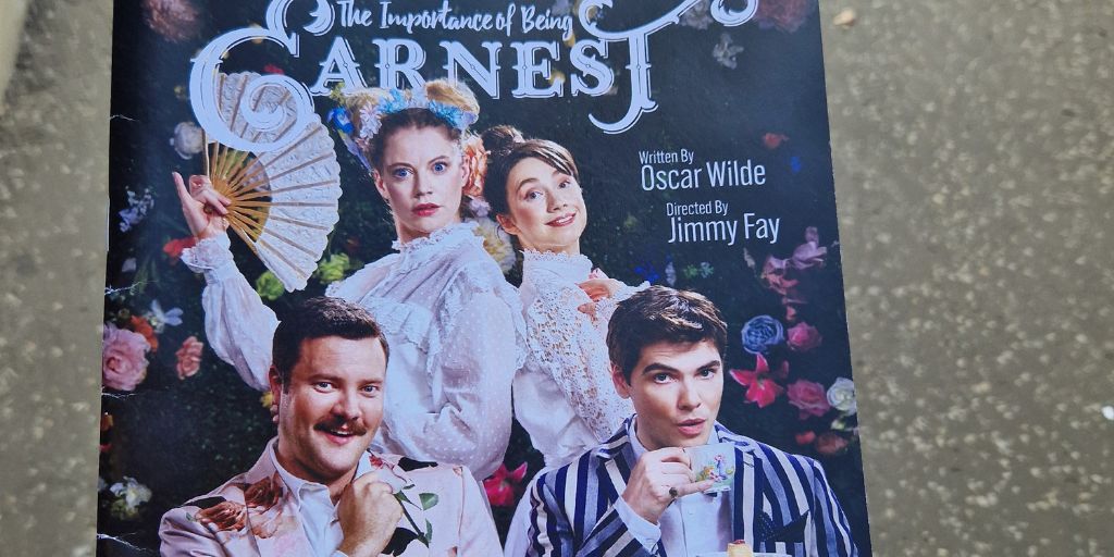Photo of the programme for the play The Importance of Being Earnest. Featuring the main four characters in full costume
