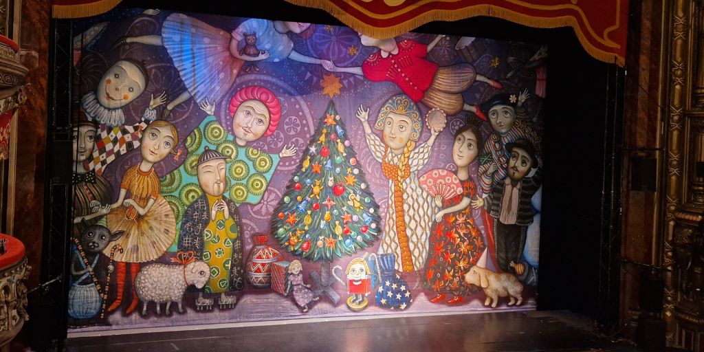 Colour painted backdrop of characters gathered around a Christmas Tree for The Nutcracker Ballet.